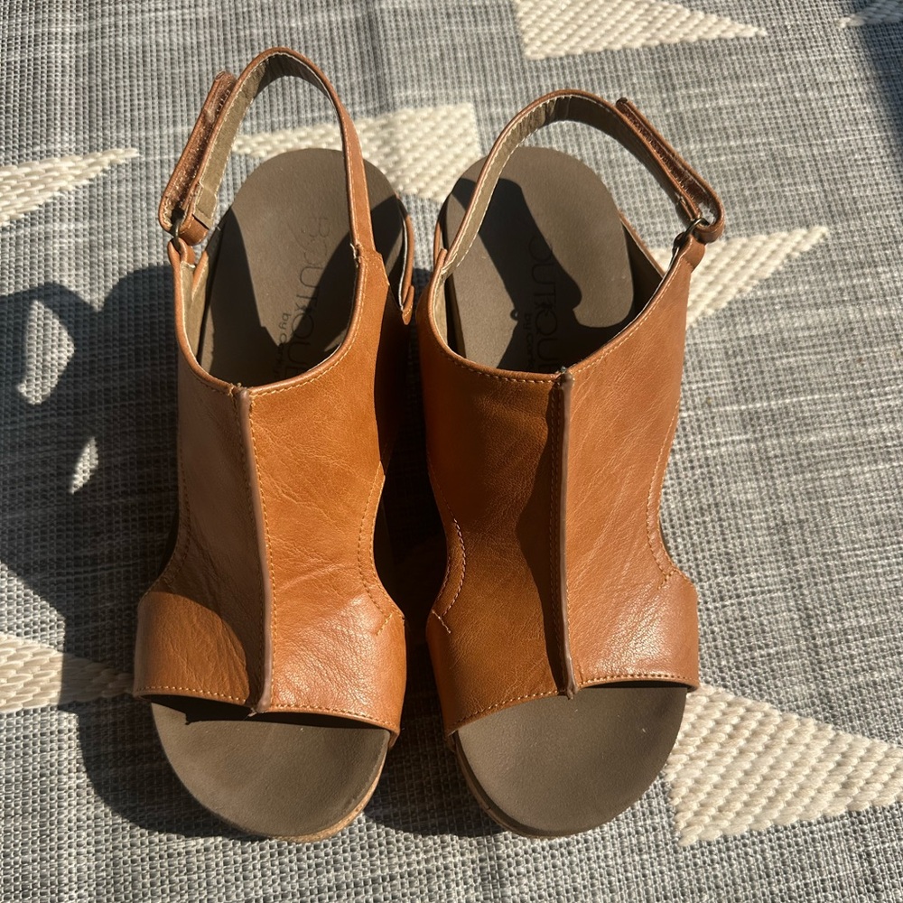 A pair of brown sandles with a little heal.